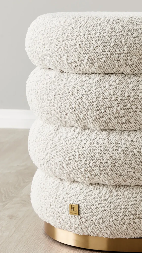 A cream bouclé ottoman positioned on a faded vintage rug in a living room